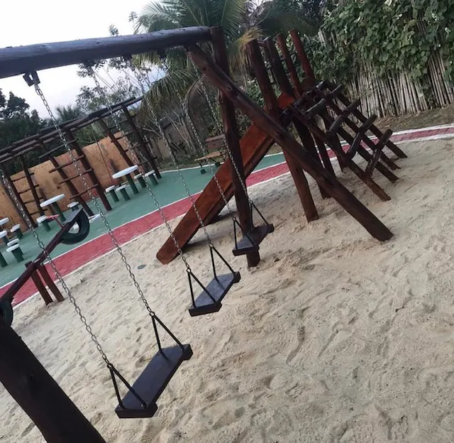 Balanços de madeira sobre areia na área comum de um resort