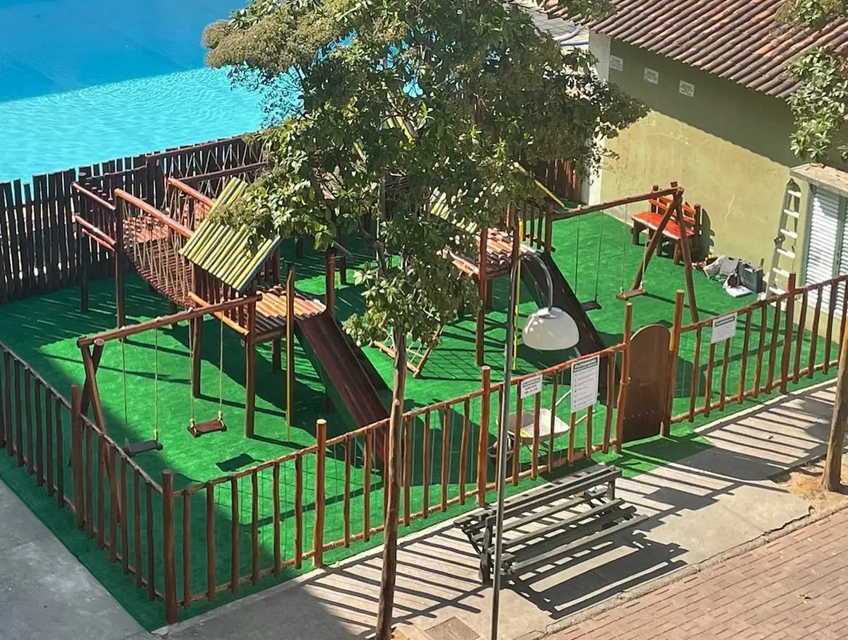 Playground de madeira PHD em escola com grama sintética instalado conforme NBR 16071 com demarcações de segurança