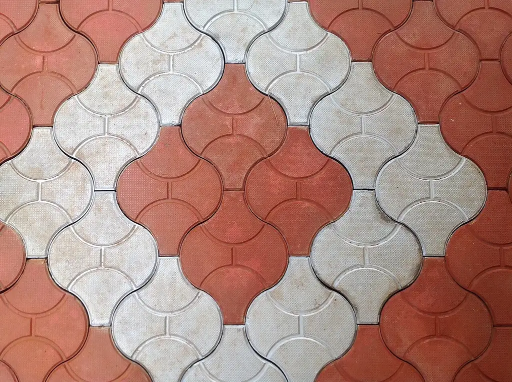 Piso intertravado de concreto em peças vermelhas e cinza formando um desenho colorido