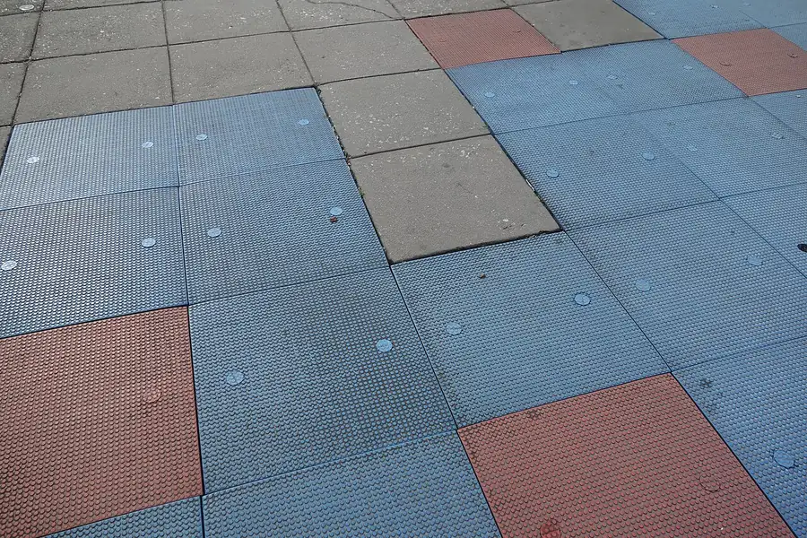 Piso de placas modulares de borracha em azul, vermelho e cinza em área de playground