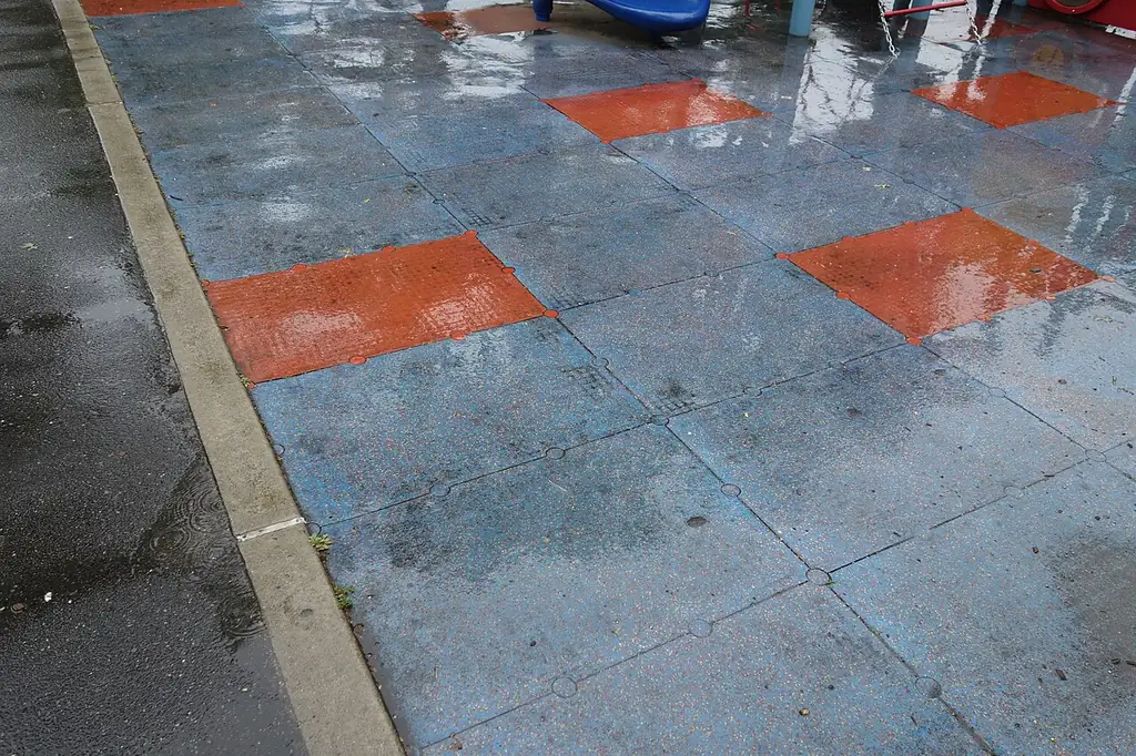 Placas modulares de borracha azuis com peças laranja em playground, mostrando a variedade de cores
