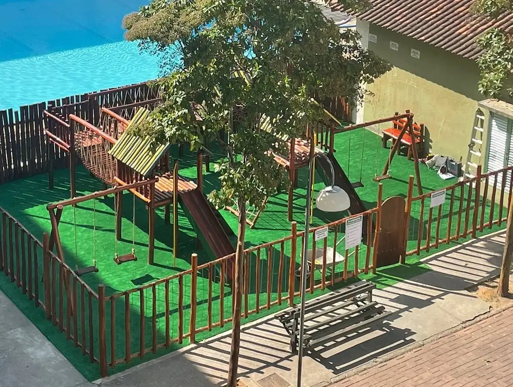 Playground de madeira com grama sintética e mural em área de escola